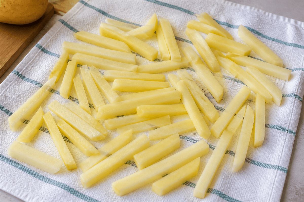 Potato sticks cut for fries drying on a towel