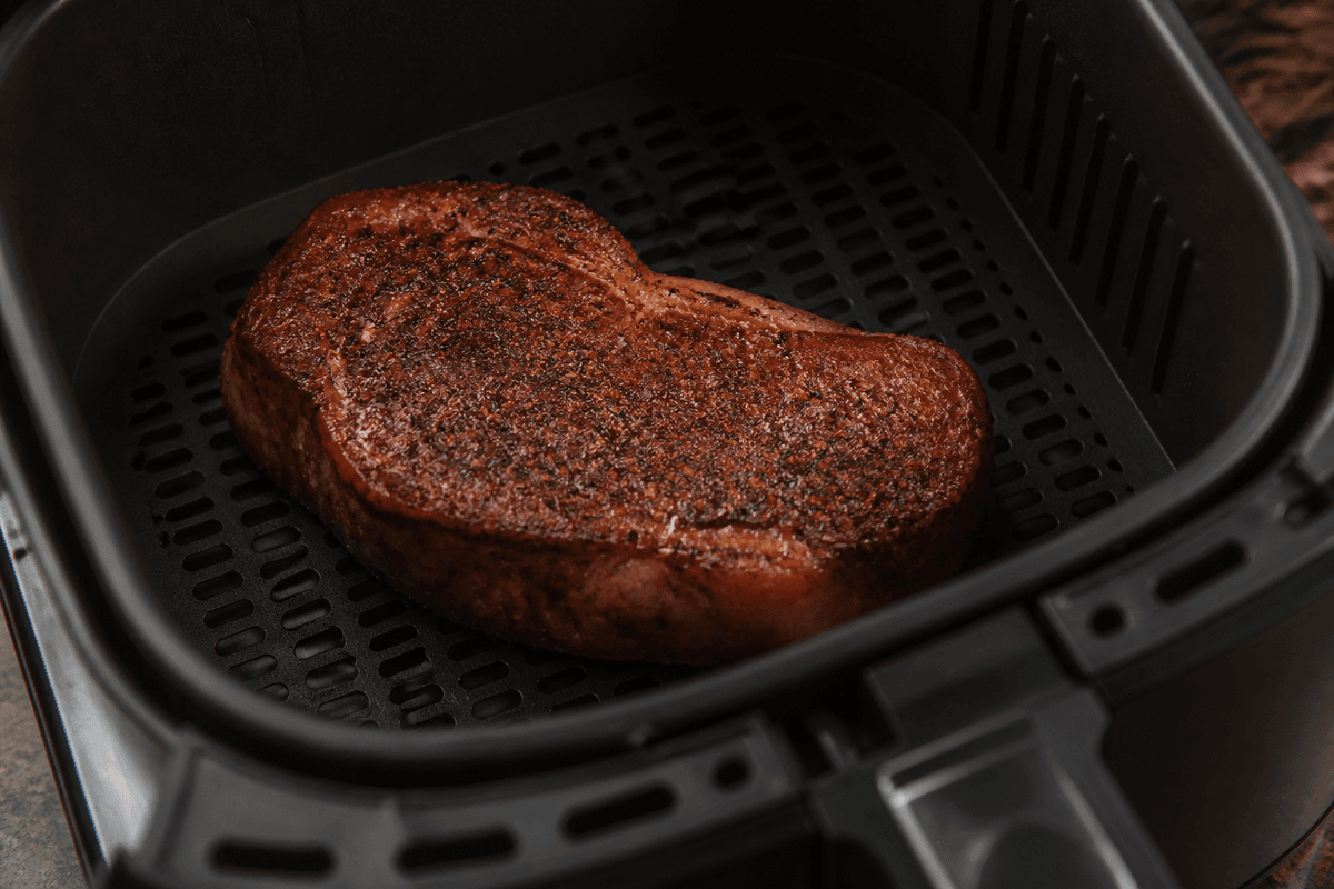 Seasoned steak in the preheated air fryer basket