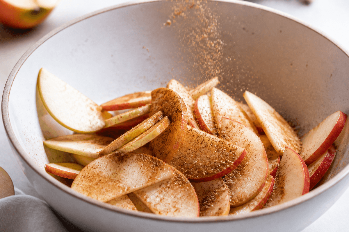 Apple slices tossed with cinnamon sugar in a bowl