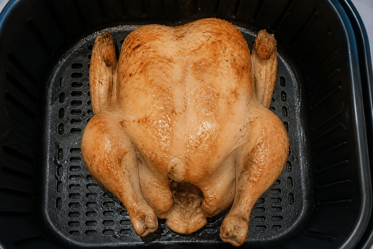 Whole chicken flipped breast-side up continuing to cook in the air fryer